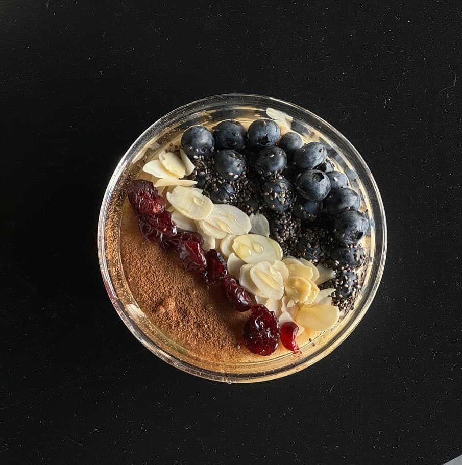Overhead bowl of blueberries, almonds and cinnamon on a black ground.